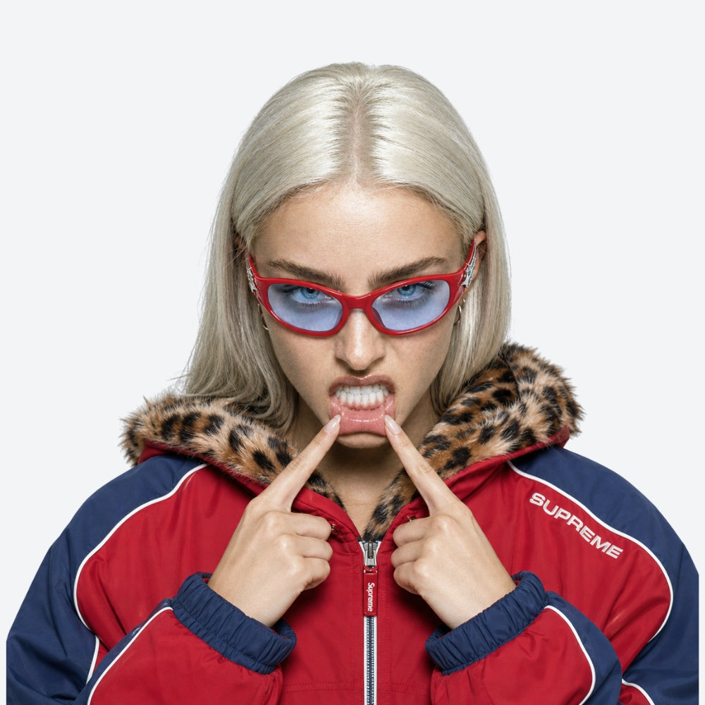 Person wearing a red and blue jacket with a leopard print hood and VYSER Red sunglasses with a decorative arm on a white background