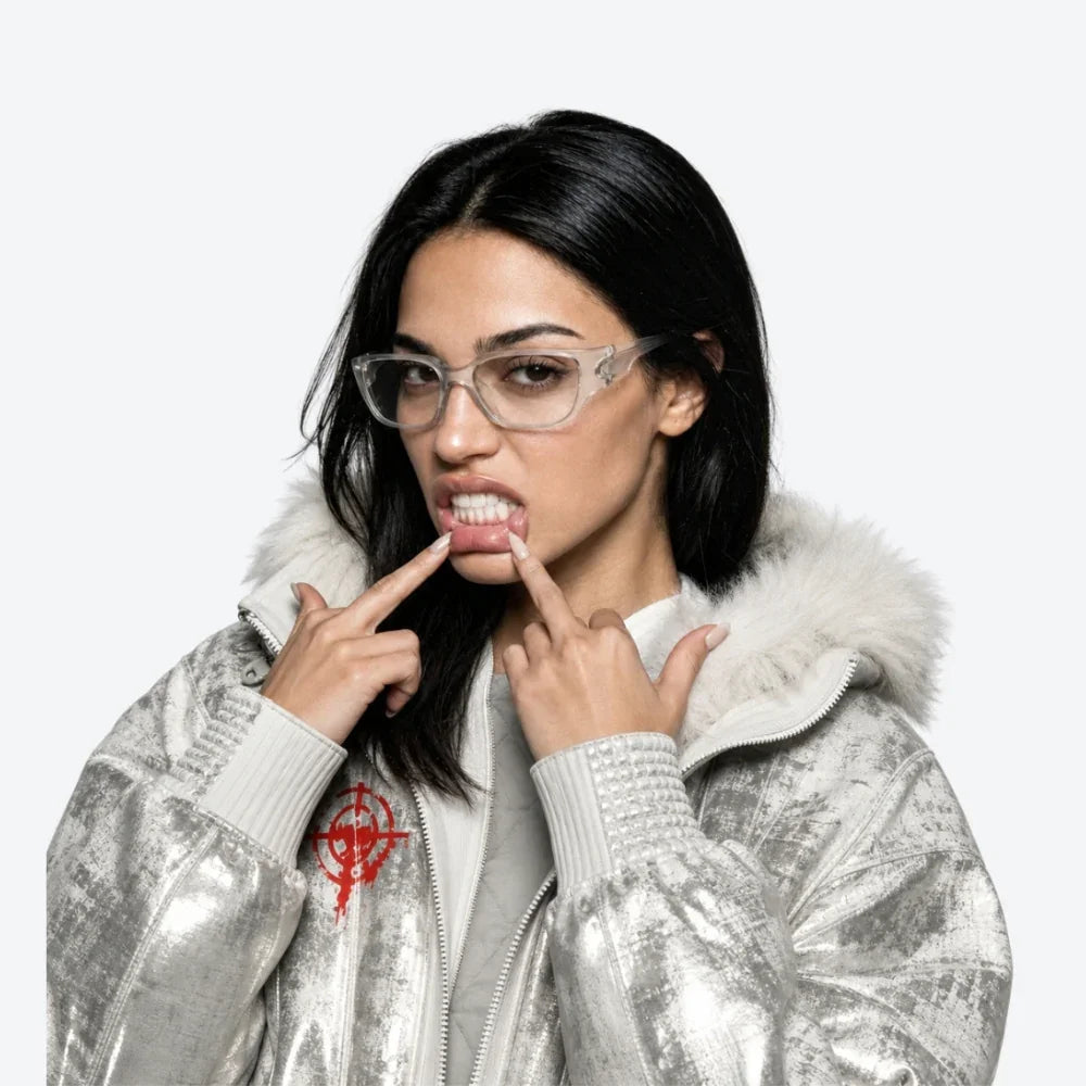 Woman wearing a silver jacket with a fur-lined hood, posing with VYSER translucent white rectangular eyewear with sleek streetwear frames and subtle gradient lenses on a white background.