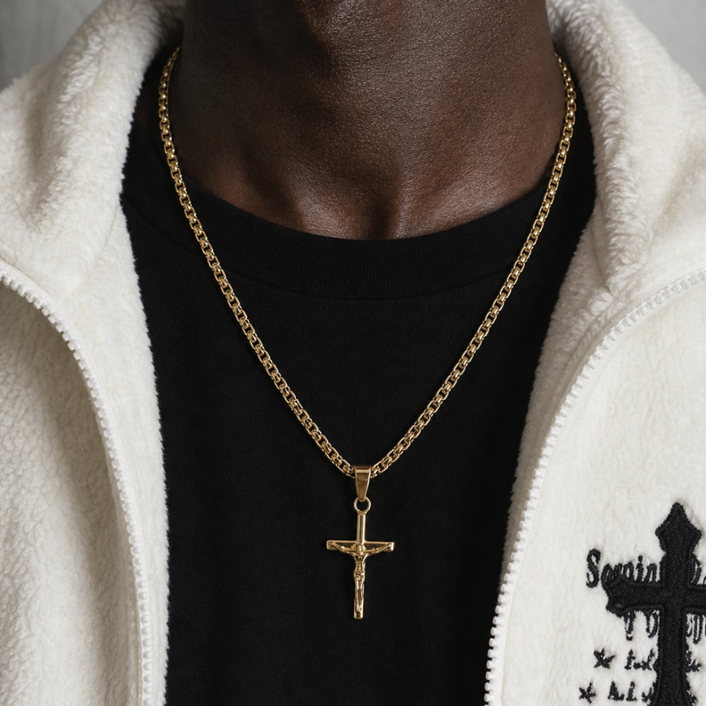 GOLD. A gold crucifix pendant necklace worn by a model in a black t-shirt and white fleece hoodie.