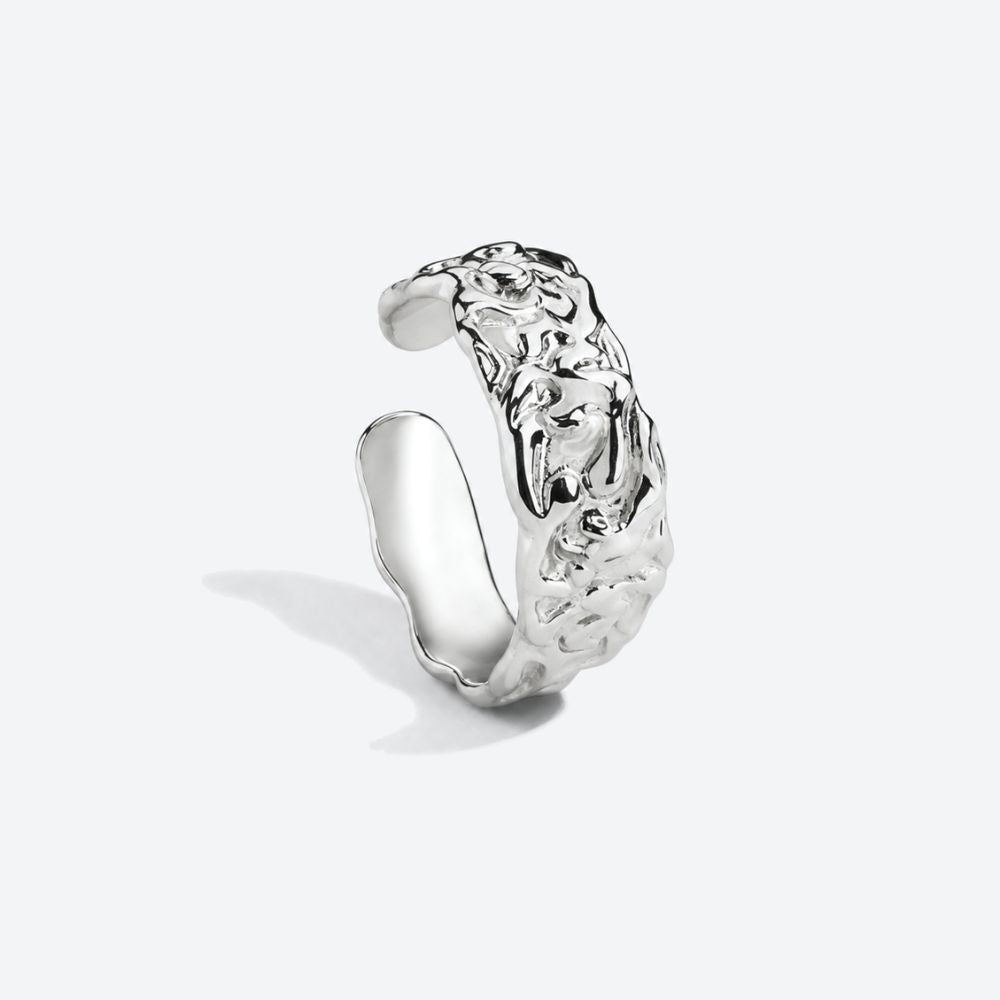 A polished silver open cuff ring with a highly textured, organic, wavy surface, photographed on a clean light gray background.