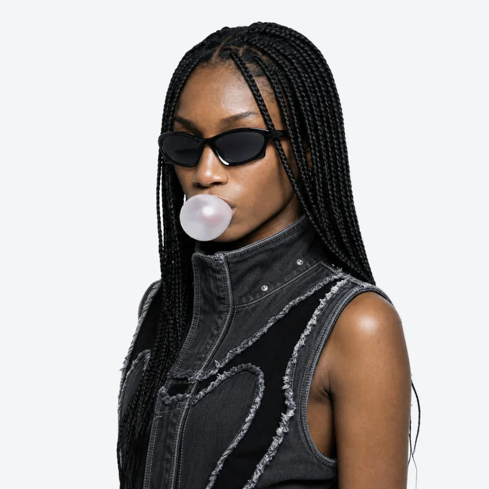 VYSER black cat-eye sunglasses with sleek frame, worn with distressed denim vest and bubblegum, streetwear style.