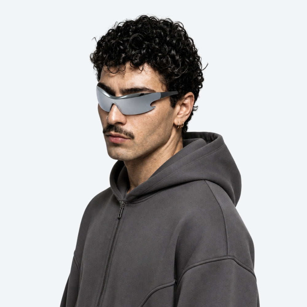 Person wearing a dark gray hoodie and futuristic VYSER Silver sunglasses with black frame on a white background