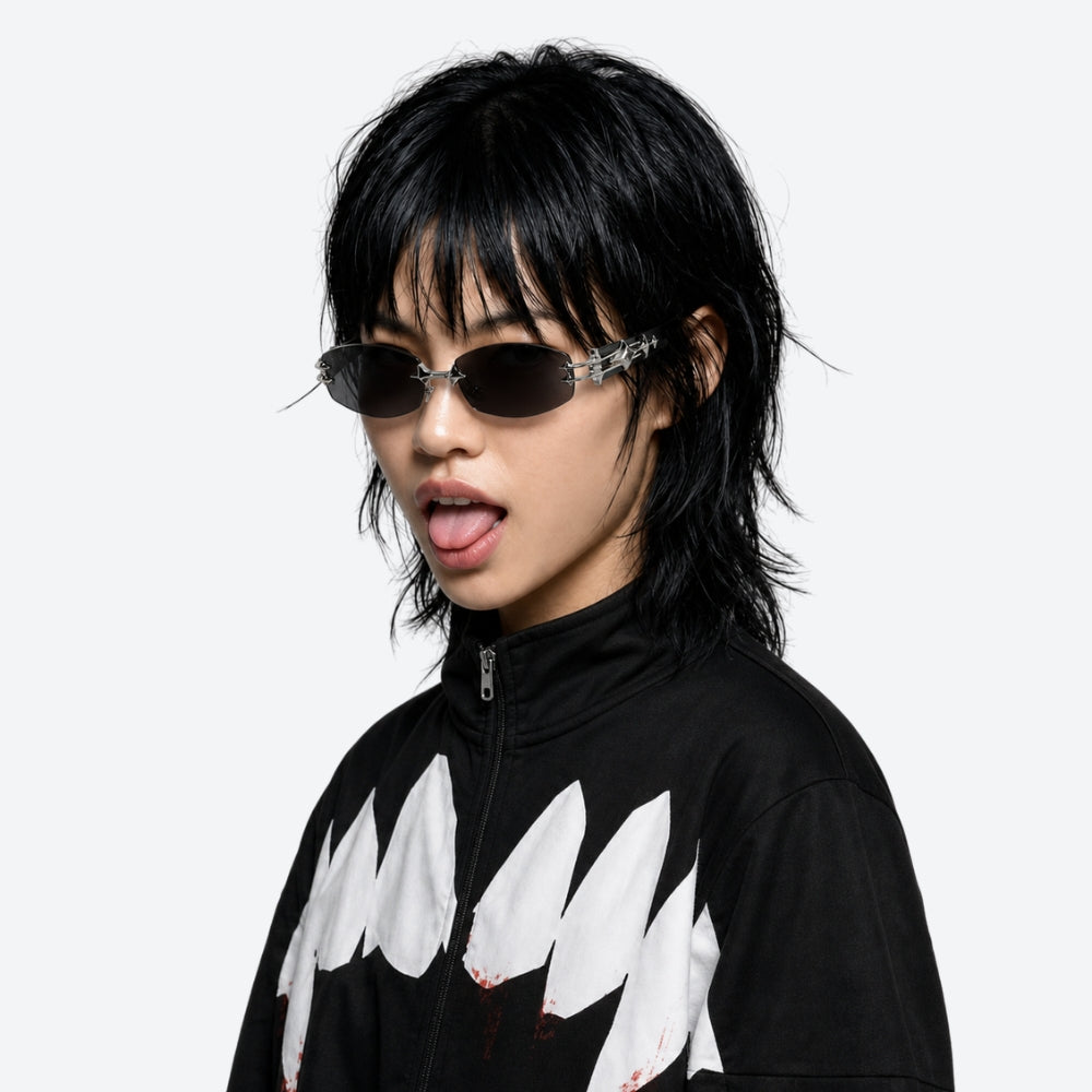 Person wearing a black outfit with white shark fin designs and VYSER Sunglasses with black frames and dark lenses on a white background
