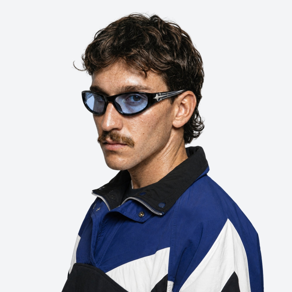 Man wearing a blue, white, and black jacket with VYSER Black sunglasses with blue lenses on a white background
