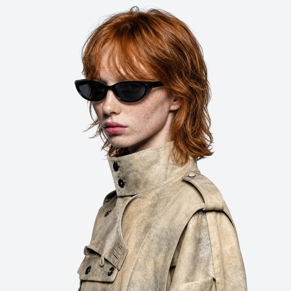 Person wearing VYSER Black sunglasses with dark lenses and a beige trench coat on a white background