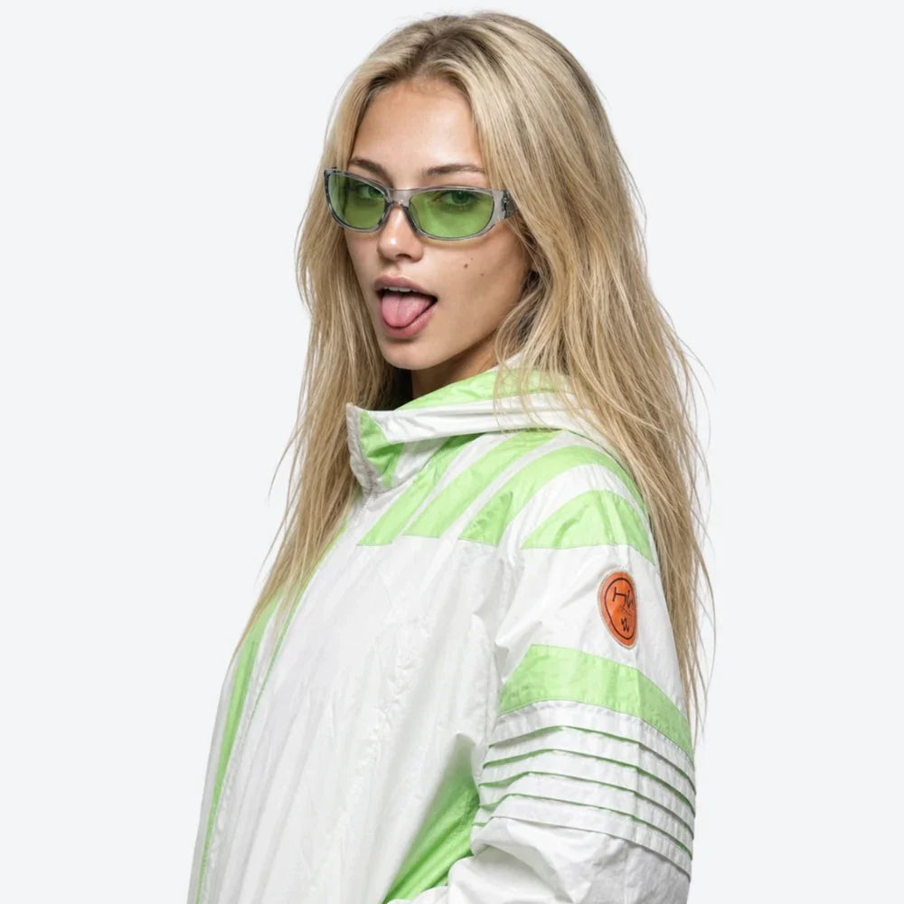 VYSER green-tinted rectangular sunglasses with clear frames, styled with a white and lime striped windbreaker jacket.