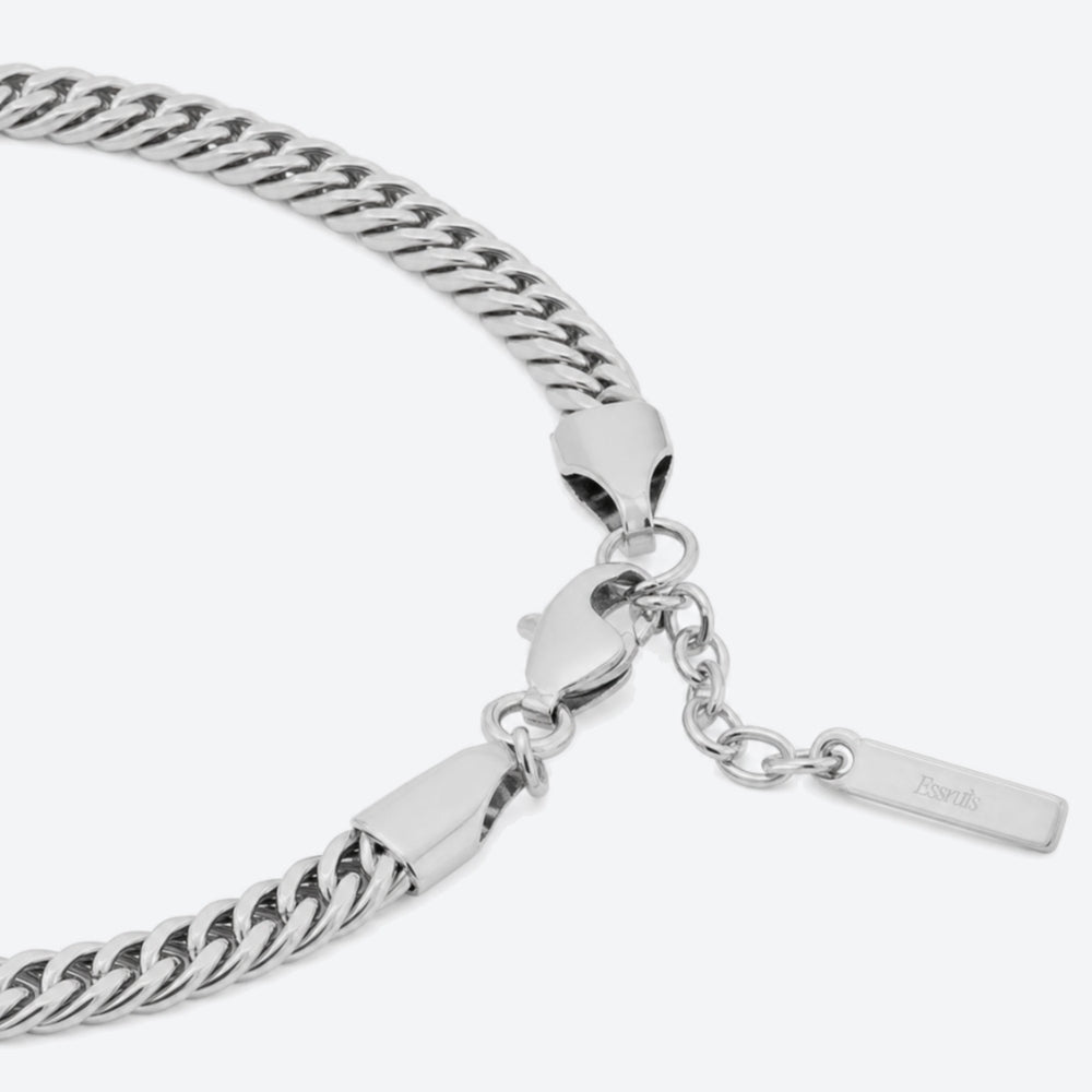 Close-up of a silver-toned chain bracelet with a lobster clasp, extender chain, and a small rectangular tag engraved with the brand name 'Peach'.
