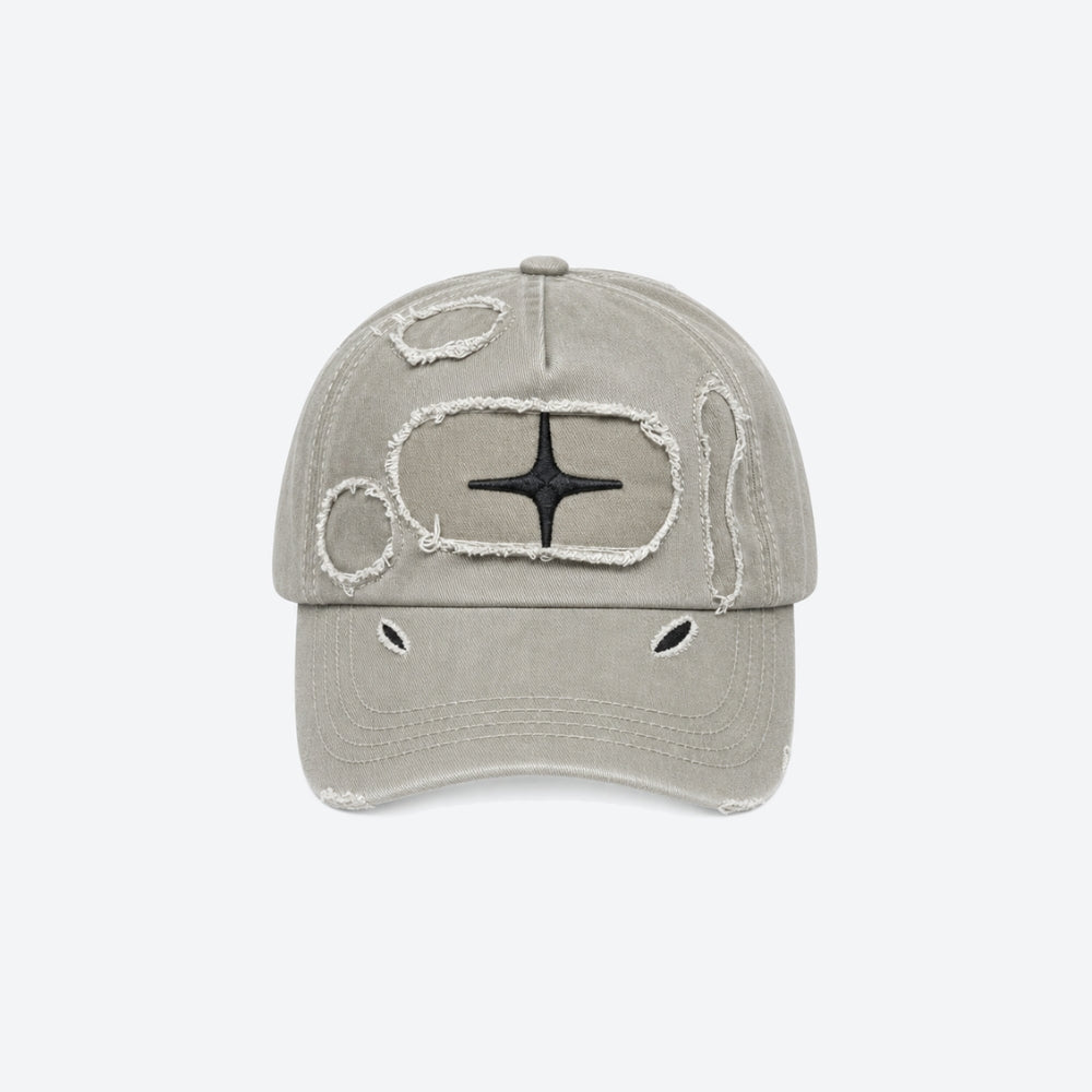 A distressed baseball cap in a light grayish-beige color, featuring a black star emblem surrounded by a frayed white border on the front panel, with additional distressed details on the brim and crown, set against a plain light gray background.