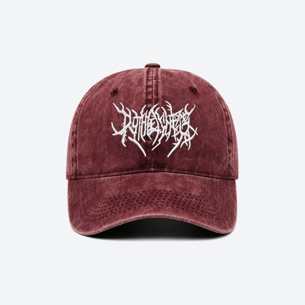 A washed burgundy baseball cap featuring a white embroidered gothic-style logo on the front, displayed against a clean white background.