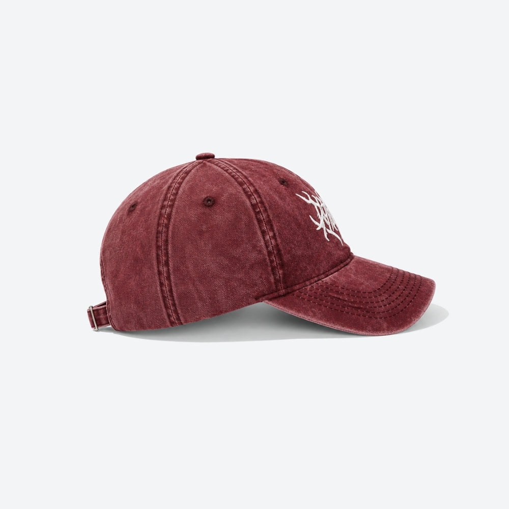 A washed burgundy baseball cap with a white embroidered graphic on the side, shown from a three-quarters angle on a light gray background.