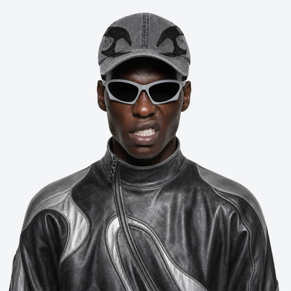 VYSER sleek gray cat-eye sunglasses with black lenses, styled with a denim cap and leather moto jacket.
