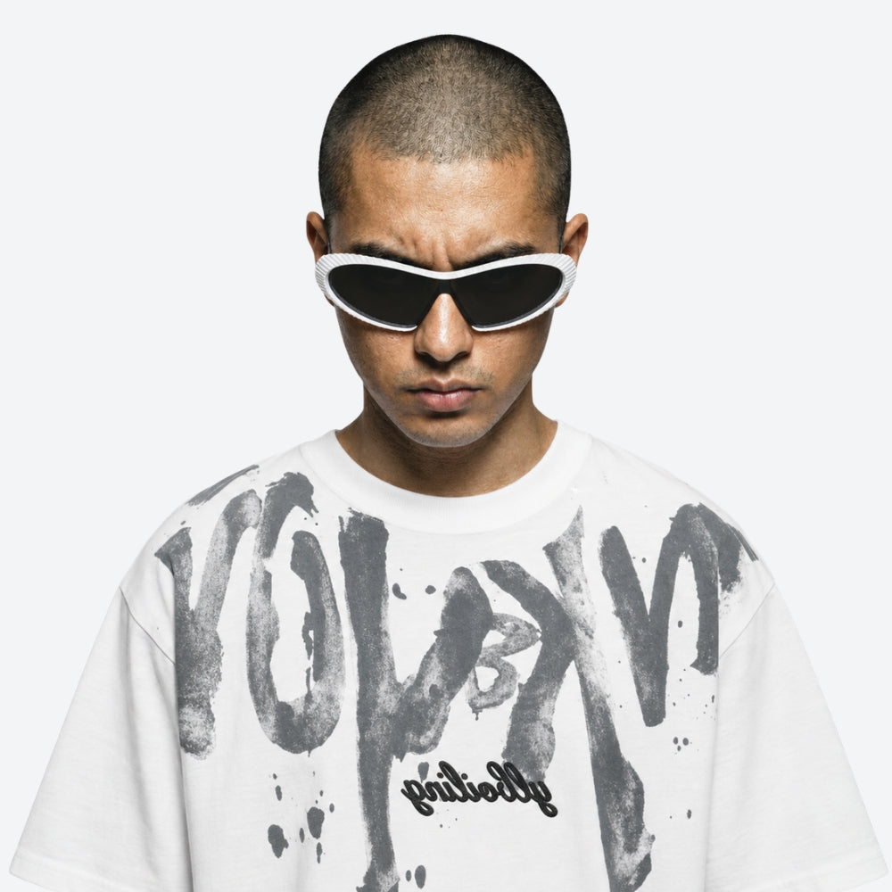 Person wearing a white t-shirt with black text and VYSER white Sunglasses with hexagonal lenses on a white background
