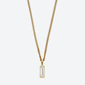 A gold chain necklace with a rectangular clear baguette-cut gemstone pendant, shown against a light gray background.