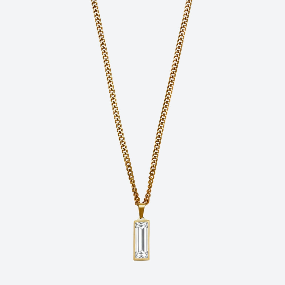 A gold chain necklace with a rectangular clear baguette-cut gemstone pendant, shown against a light gray background.
