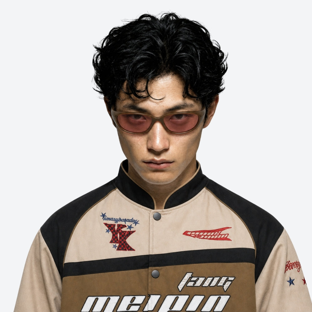Person wearing a stylish jacket with VYSER Brown sunglasses with brown-tinted lenses on a plain background