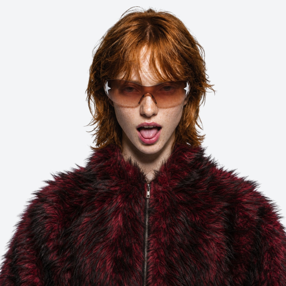 Person wearing a red fur coat and VYSER Sunglasses with a gradient brown lens on a white background