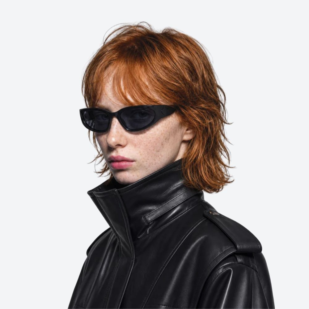 Person wearing a black leather jacket and VYSER Black sunglasses with dark lenses on a white background