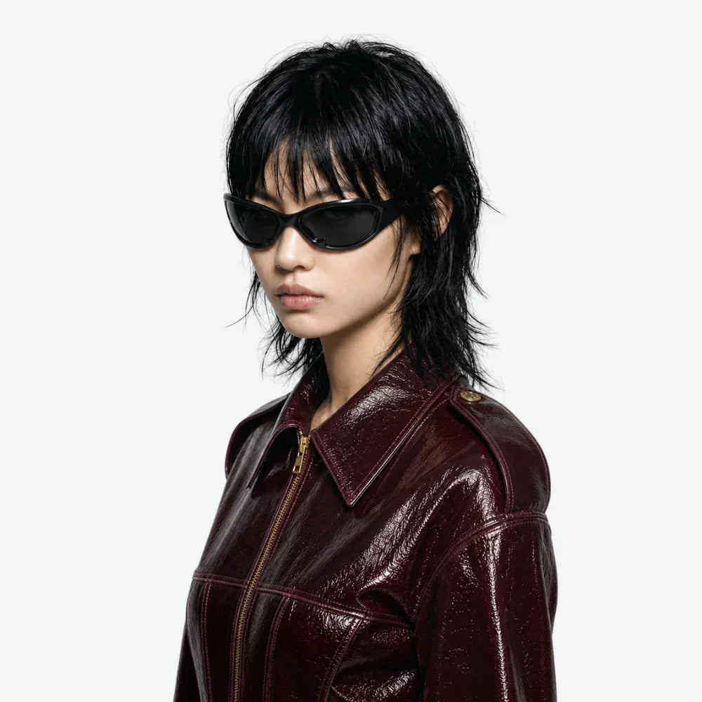 VYSER black cat-eye sunglasses with glossy finish, styled with burgundy leather jacket for edgy streetwear look.