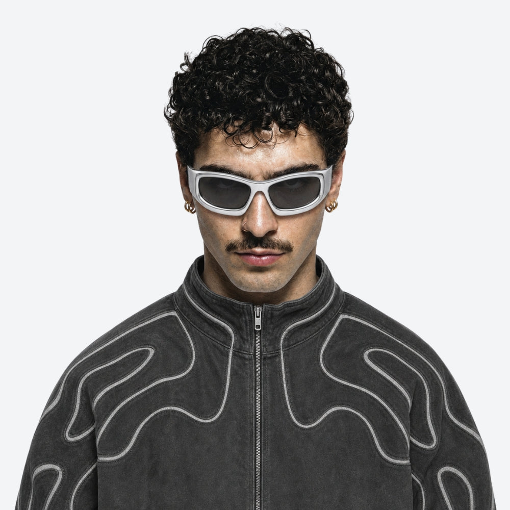 Person wearing a dark gray jacket with abstract patterns and white VYSER White sunglasses with gray lenses on a white background